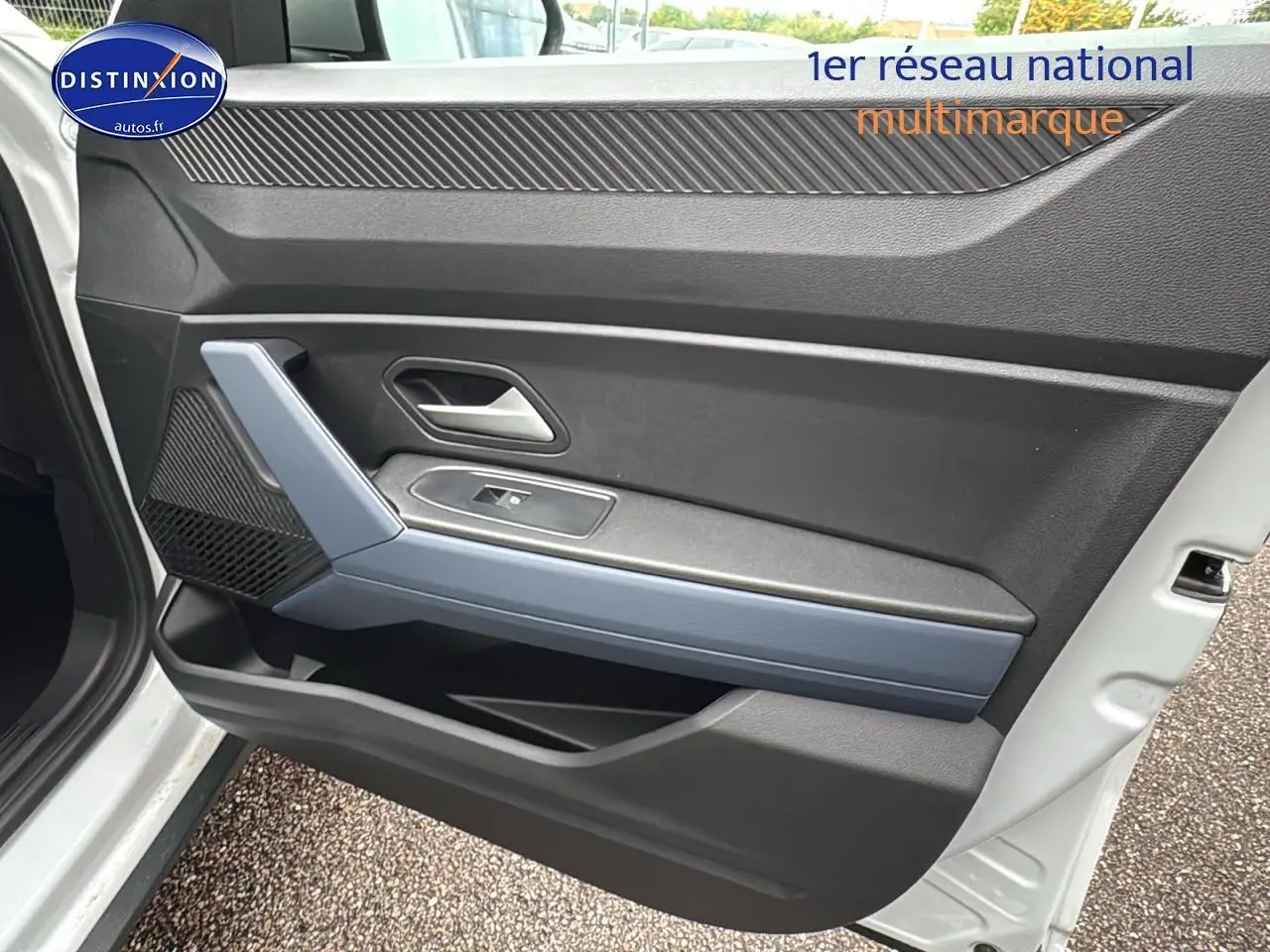 Intérieur côté gauche de la porte avant d'un Dacia Duster blanc Arctic, avec poignée argentée et accoudoir gris.