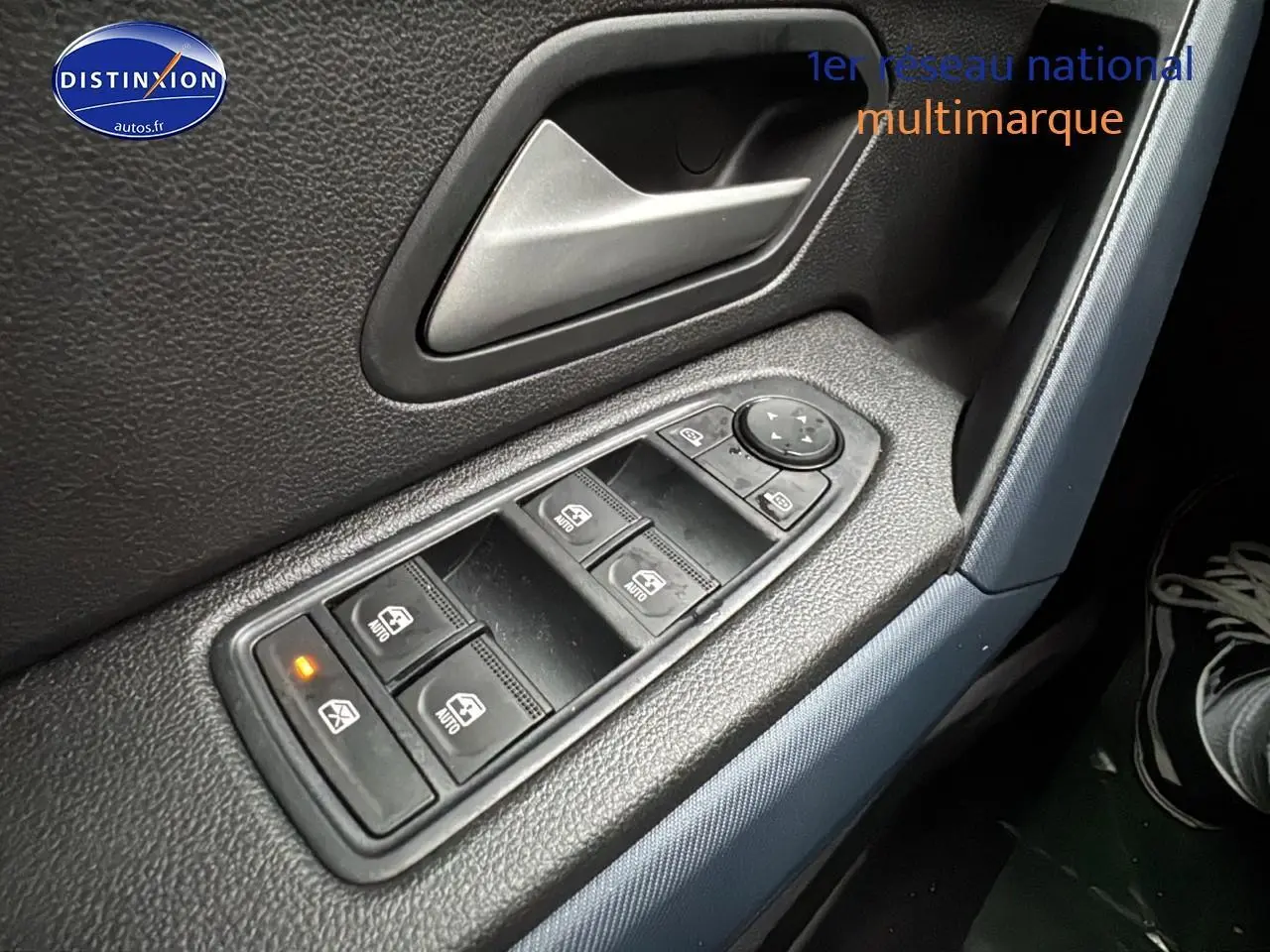 Gros plan sur les commandes des vitres électriques côté conducteur du Dacia Duster blanc Arctic 2025.