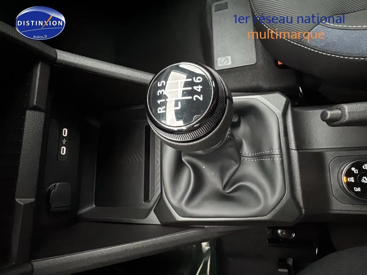 Gros plan sur le levier de vitesses manuel noir du Dacia Duster blanc Arctic, avec console centrale et accoudoir visible.