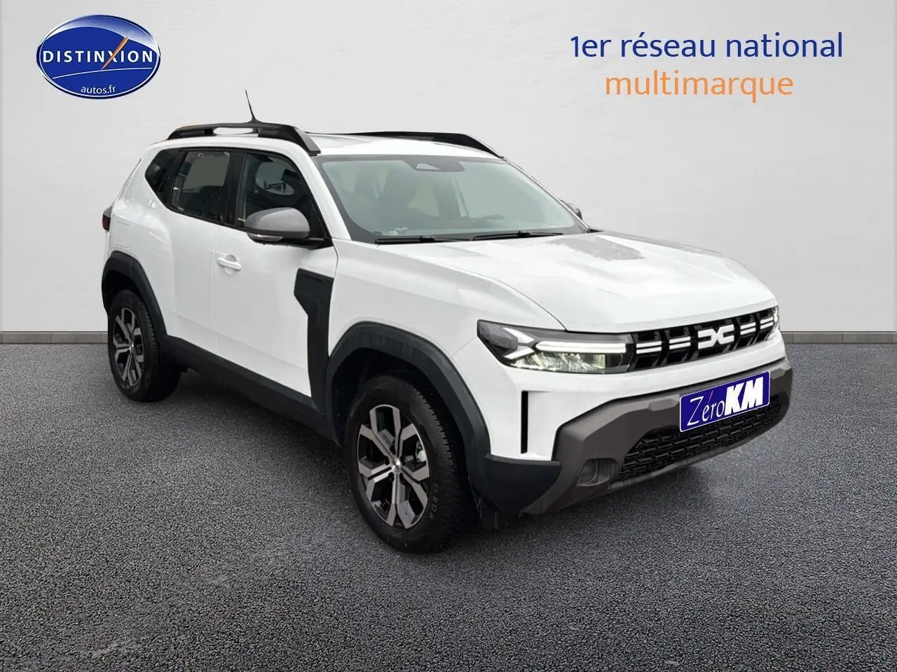 Vue 3/4 avant droit du Dacia Duster blanc Arctic avec barres de toit et jantes alu distinctives.