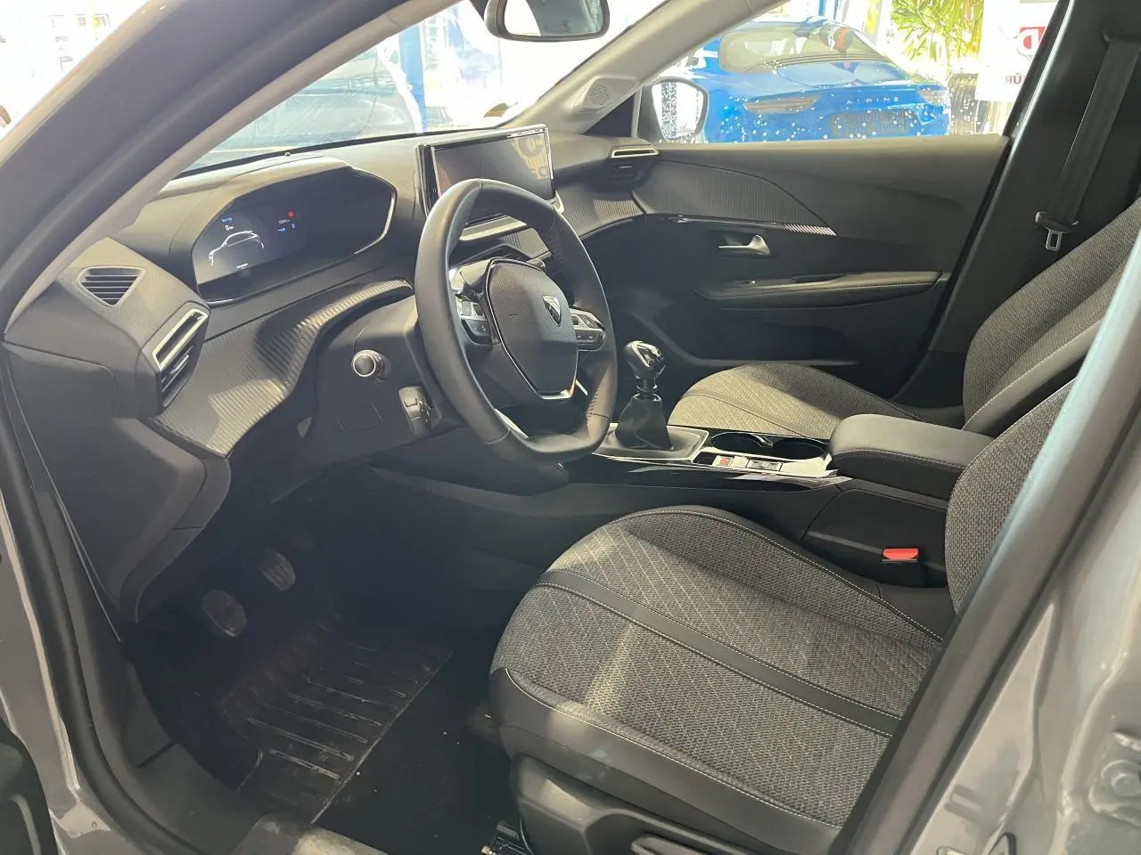 Intérieur avant droit du Peugeot 208 gris clair Selenium, volant compact cuir et sièges tissu gris avec surpiqûres Quartz