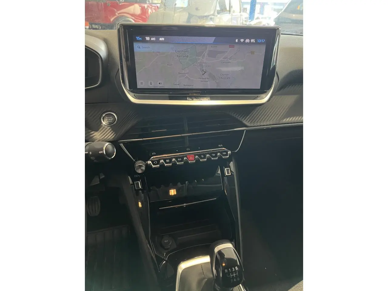 Intérieur Peugeot 208 2024, vue centrale sur console avec écran tactile, commandes piano et levier de vitesse manuel.