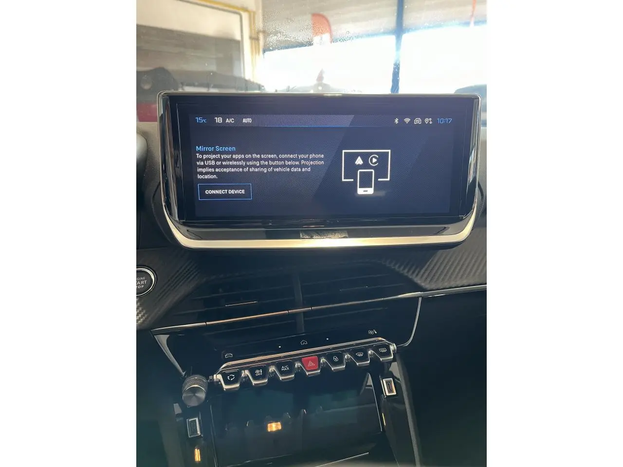 Vue rapprochée de la console centrale et écran tactile du Peugeot 208 gris clair Selenium, avec commandes et finition carbone.