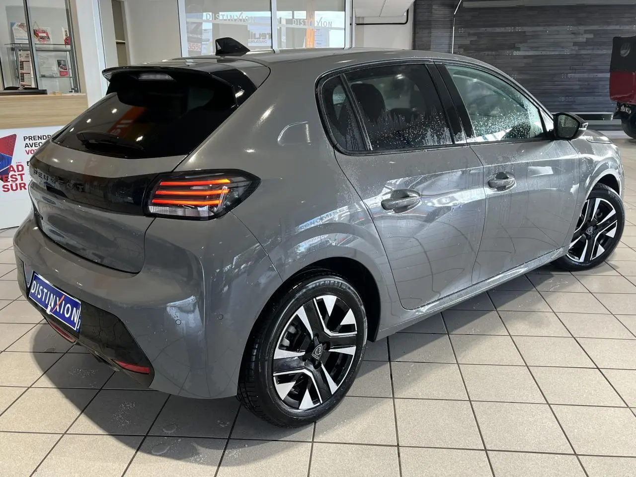 Vue 3/4 arrière droite de la Peugeot 208 gris clair Selenium avec feux arrière LED 3 griffes et jantes alliage 16 pouces.