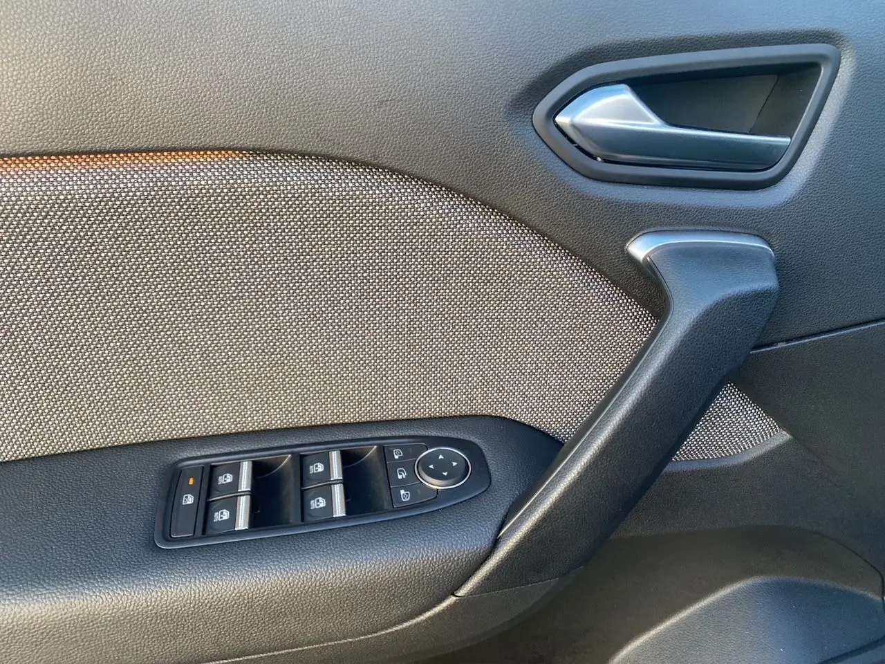 Détail de la porte côté conducteur avec commandes des vitres et poignée en plastique noir dans Renault Symbioz gris Casiopee.