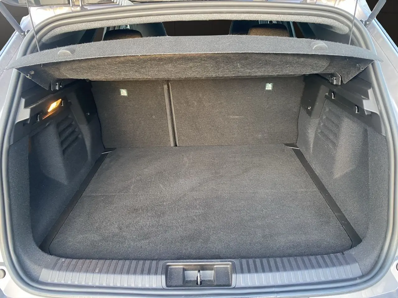 Coffre ouvert vu de l'arrière d'une Renault Symbioz gris Casiopee, montrant l'espace de rangement et la moquette noire.