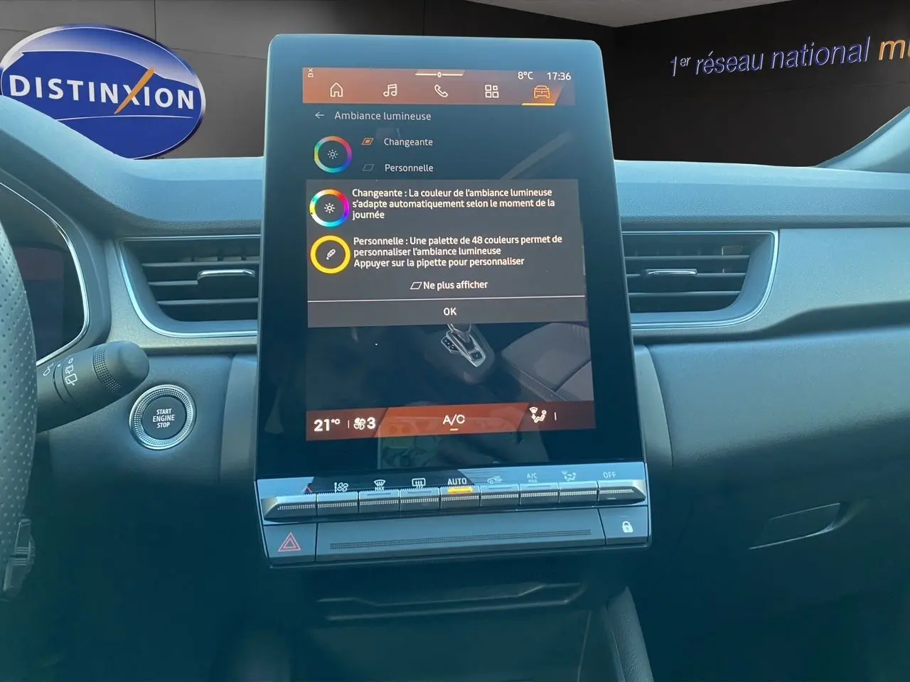 Vue intérieure centrée sur l'écran tactile vertical du tableau de bord de la Renault Symbioz gris Casiopee, avec commandes climatisation visibles.