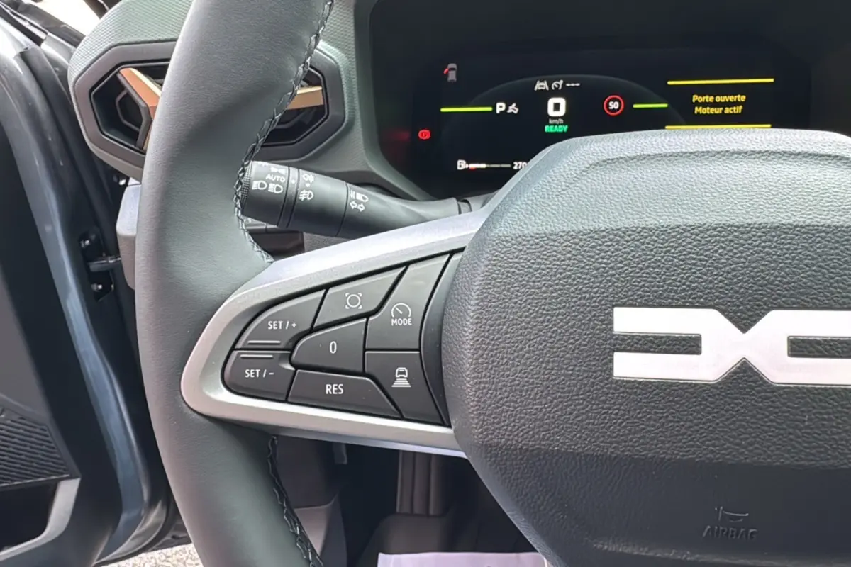 Gros plan sur le volant cuir gris schiste avec commandes multifonctions, tableau de bord digital allumé du Dacia Bigster Hybrid 155 Extreme Plus.