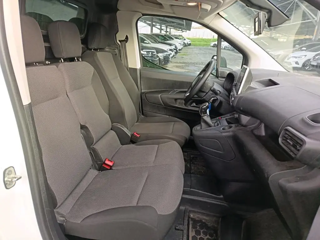 Vue intérieure côté conducteur du Citroën Berlingo blanc 2020, montrant les sièges tissu gris et le tableau de bord noir.