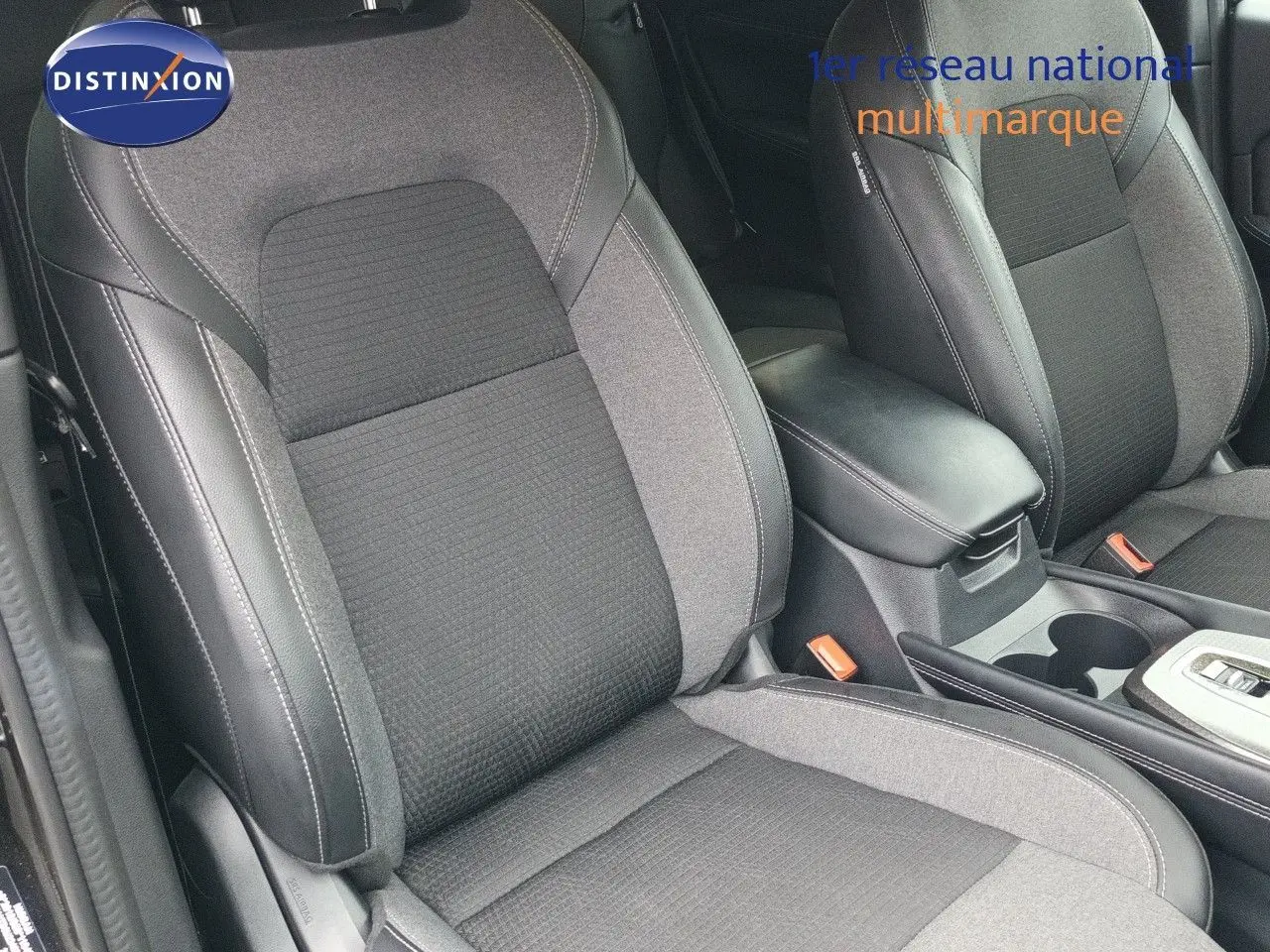 Gros plan sur les sièges avant en tissu noir et gris du Nissan Qashqai e-POWER 2025, avec accoudoir central visible.
