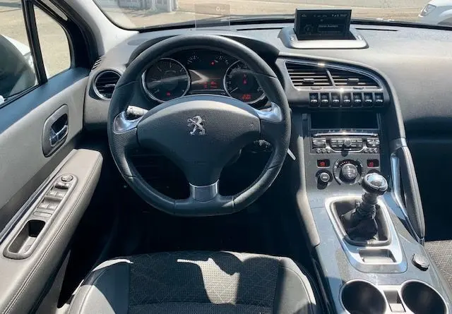 Vue intérieure du poste de conduite du Peugeot 3008 noir 2014, volant, tableau de bord et levier de vitesse manuel visibles.