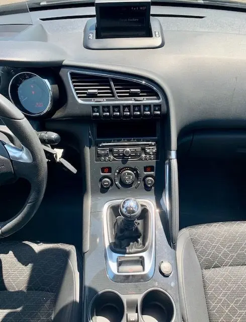 Vue intérieure centrée sur la console centrale et levier de vitesse manuelle du Peugeot 3008 noir de 2014.