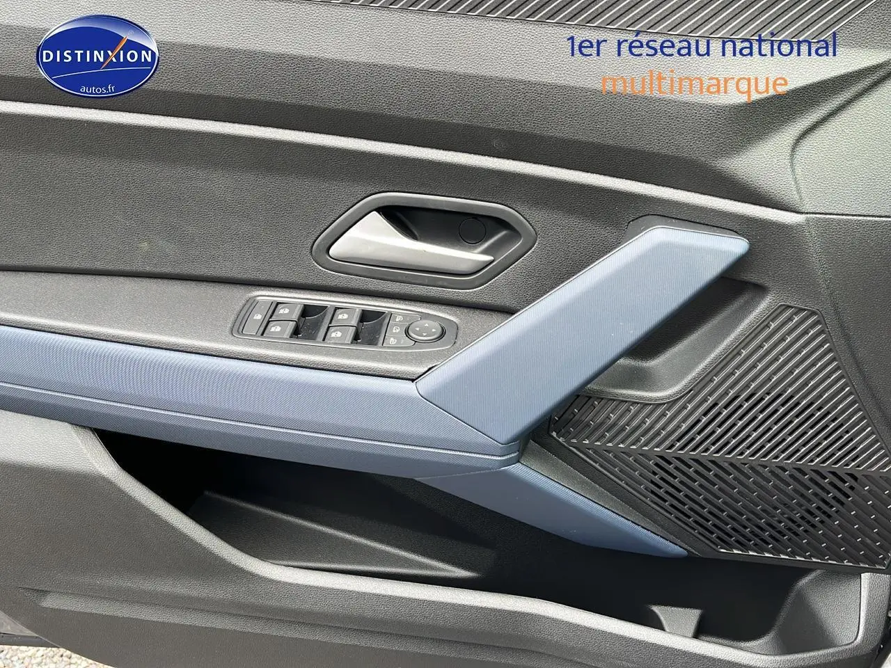 Détail de la porte avant gauche du Dacia Duster 2025 gris schiste avec accoudoir bleu et commandes électriques.