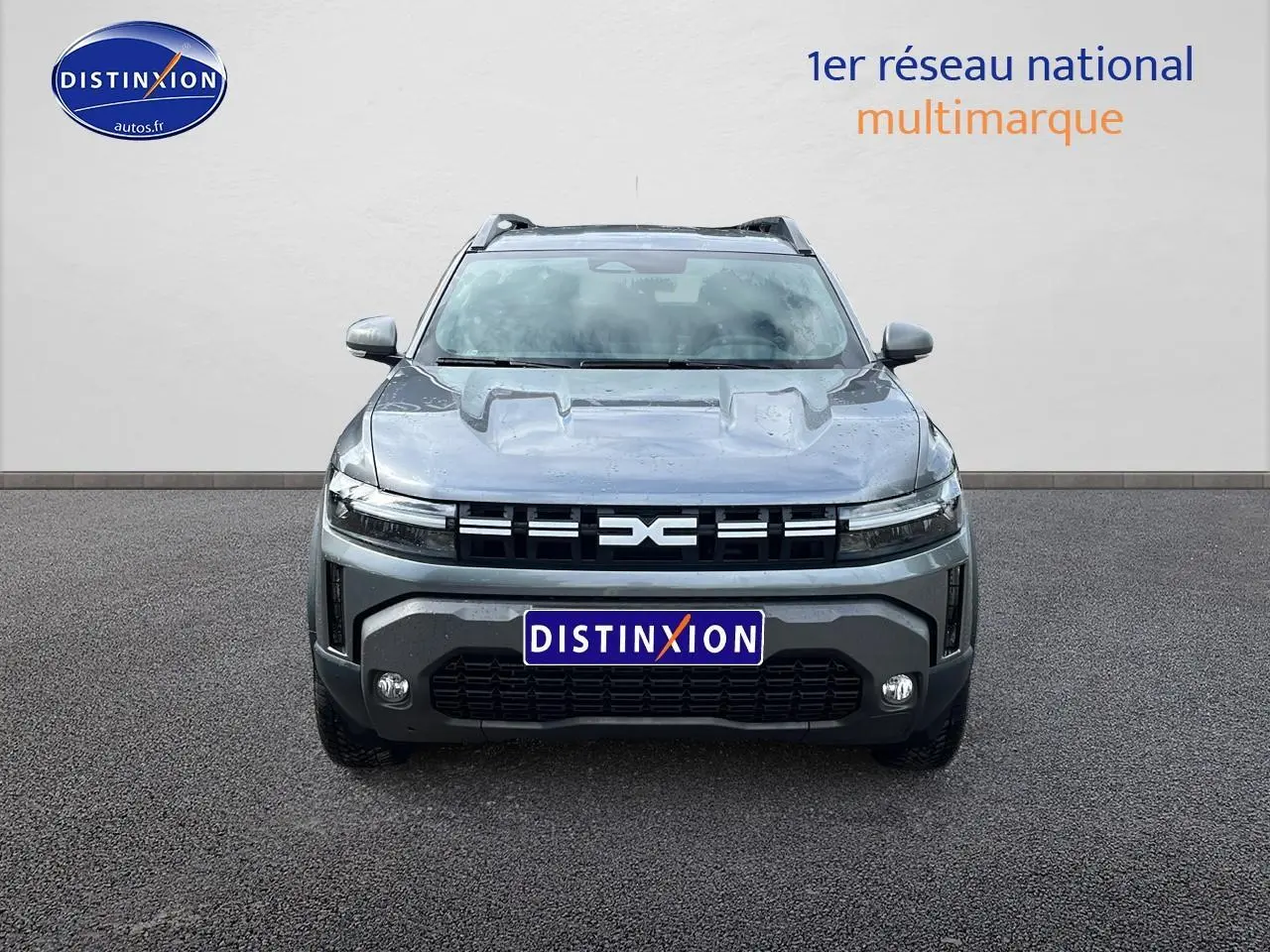 Vue de face du Dacia Duster gris schiste 2025 avec calandre distinctive et phares LED fins allumés.
