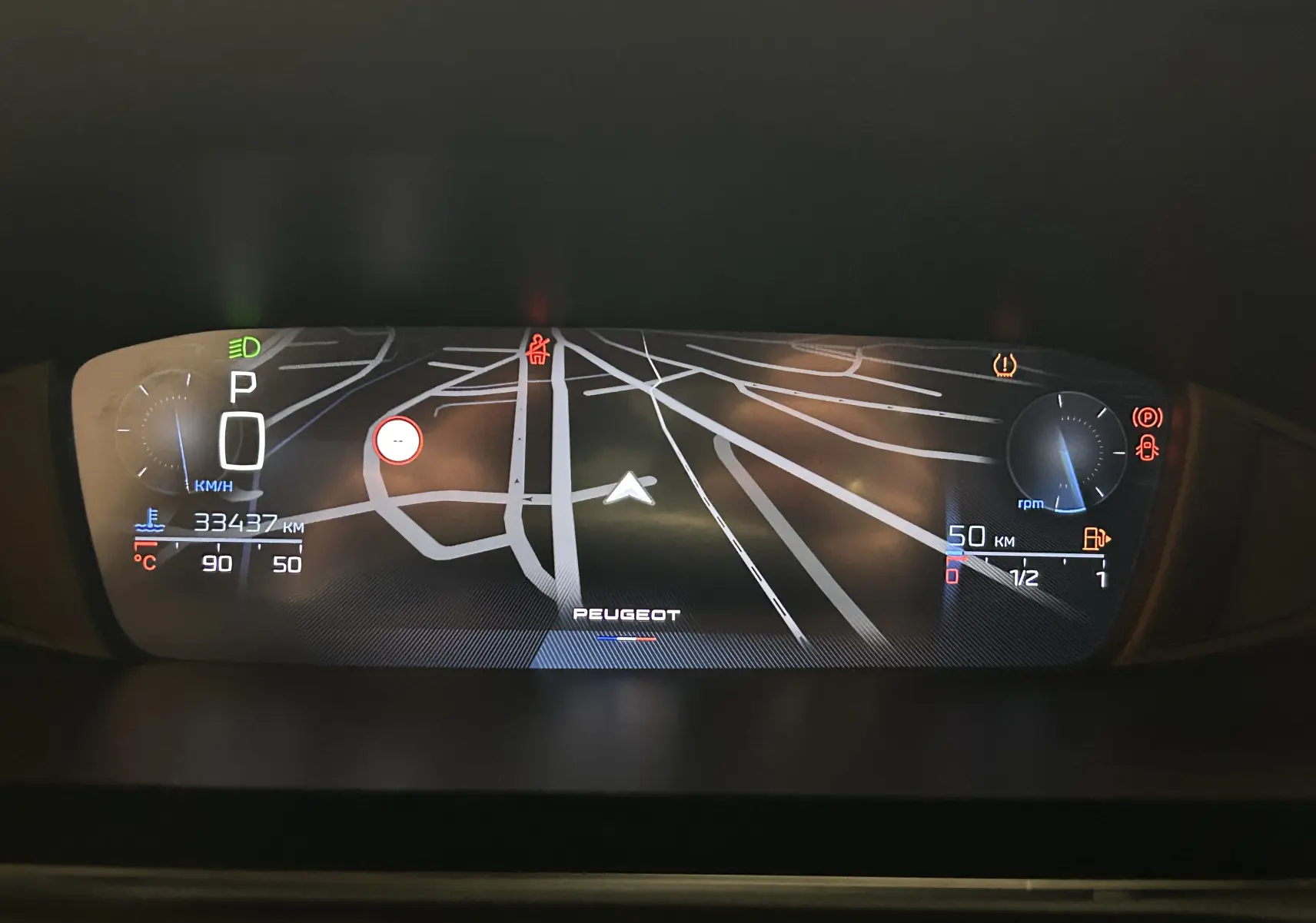 Tableau de bord numérique de Peugeot 308 rouge 2024, affichant la navigation GPS et les indicateurs de vitesse et carburant.