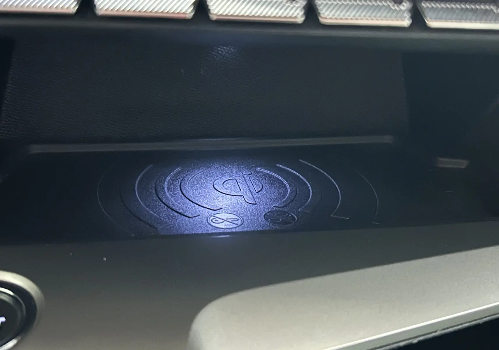 Gros plan sur le chargeur à induction noir dans l’habitacle de la Peugeot 308 rouge 2024 version BlueHDi Allure.