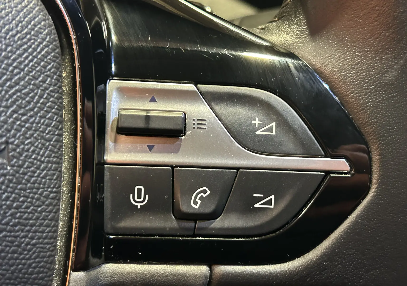 Gros plan sur les commandes du volant à gauche du Peugeot 308 2024, boutons de volume et téléphone en noir mat.