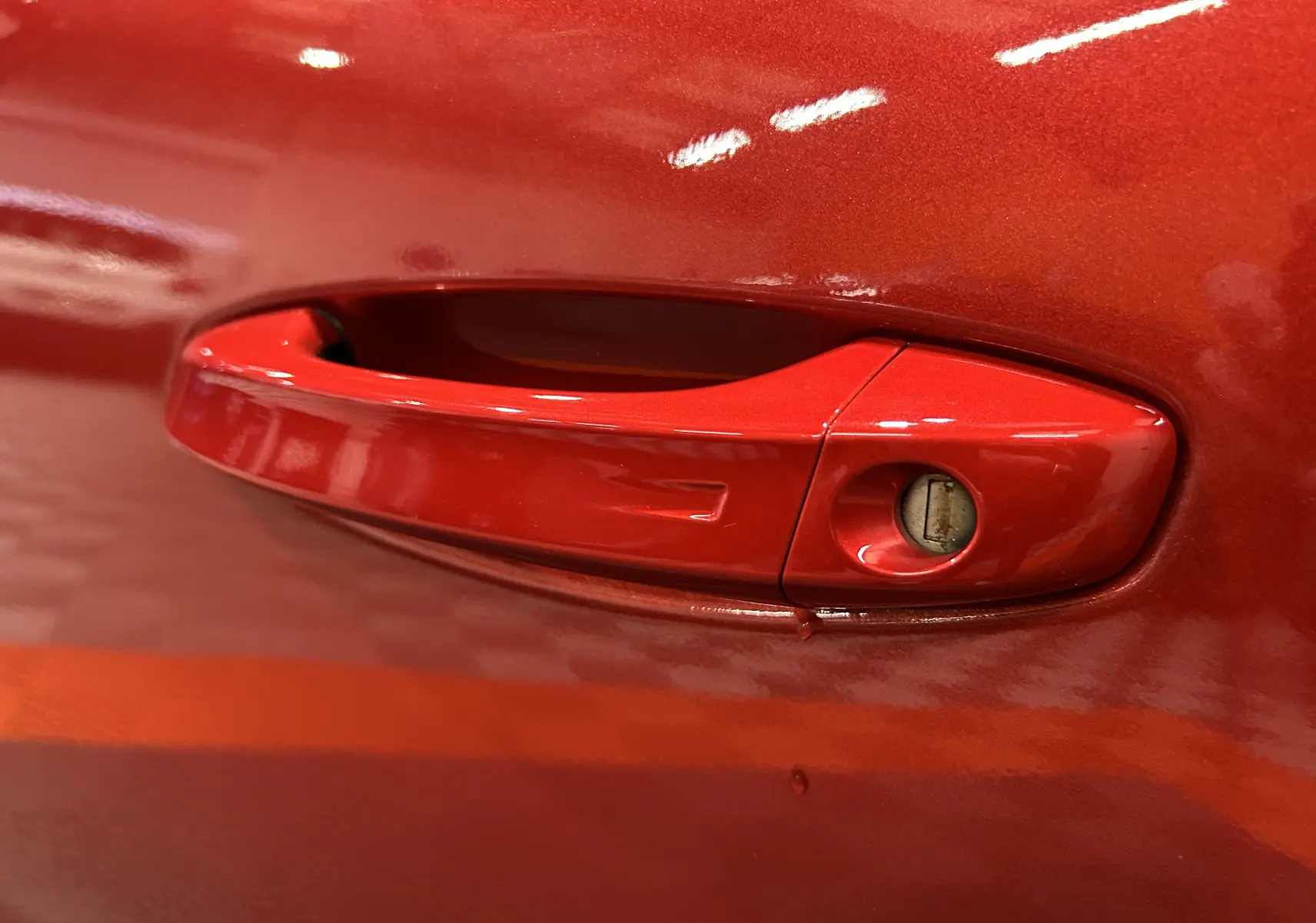 Poignée de porte rouge de la Peugeot 308 BlueHDi 130 Allure 2024, vue en gros plan sur la serrure intégrée.