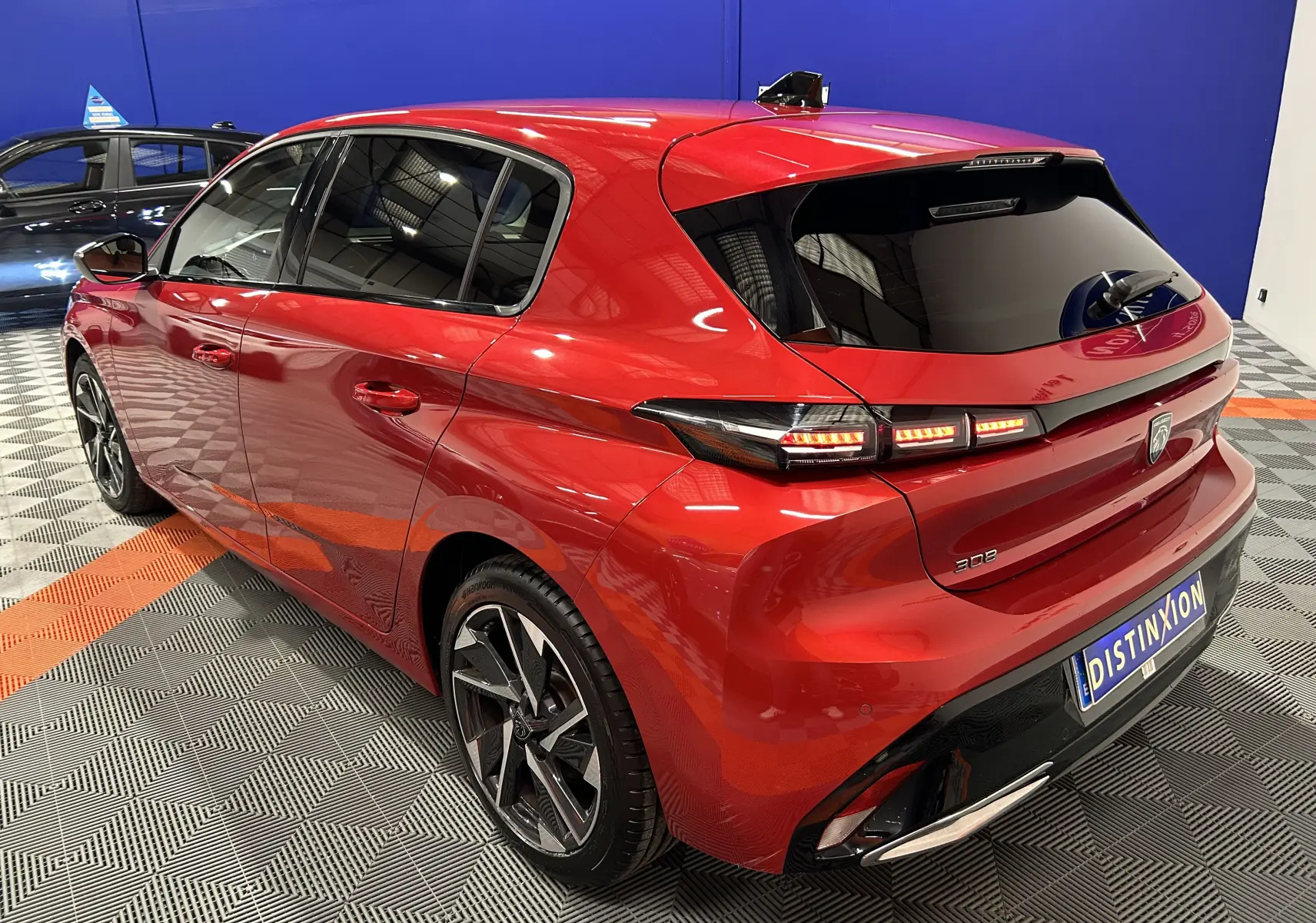 Vue 3/4 arrière droite d'une Peugeot 308 rouge 2024 avec feux LED et jantes alliage noires.