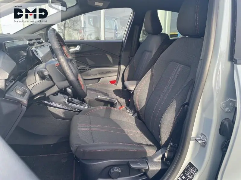 Vue intérieure côté conducteur du Ford Puma 2026 gris Cactus, sièges sport avec surpiqûres rouges et volant multifonction.