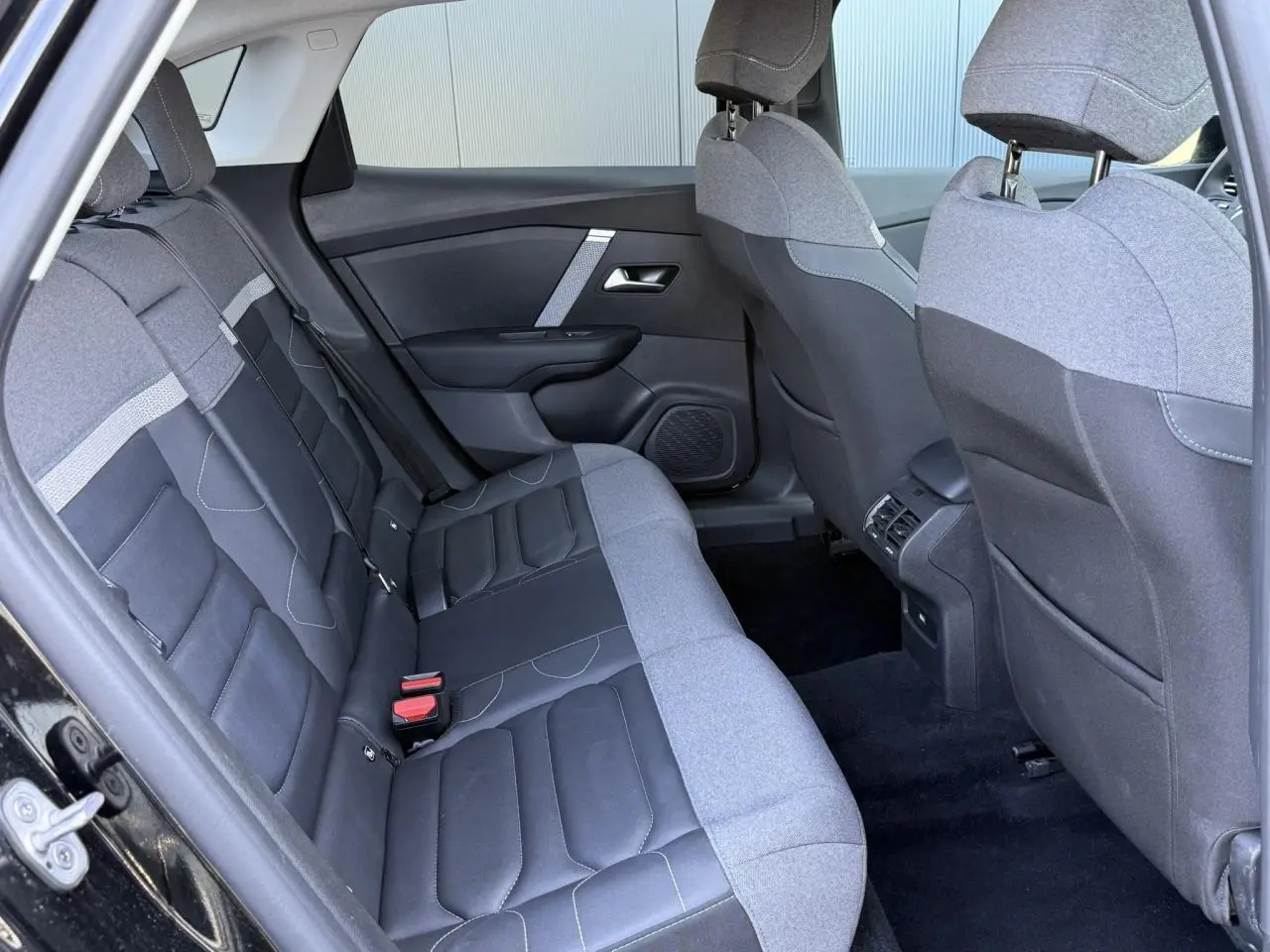 Vue intérieure arrière côté gauche de la Citroën C4 X 2024 noir Perla avec sièges bicolores tissu et cuir.