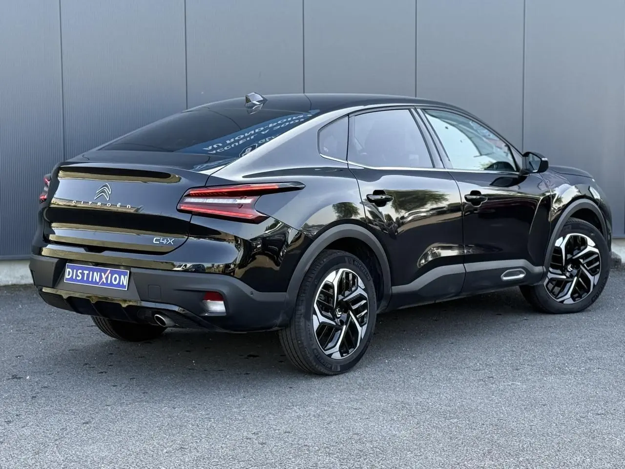 Vue 3/4 arrière droite de la Citroën C4 X noire Perla avec jantes alliage et feux LED en V distinctifs.