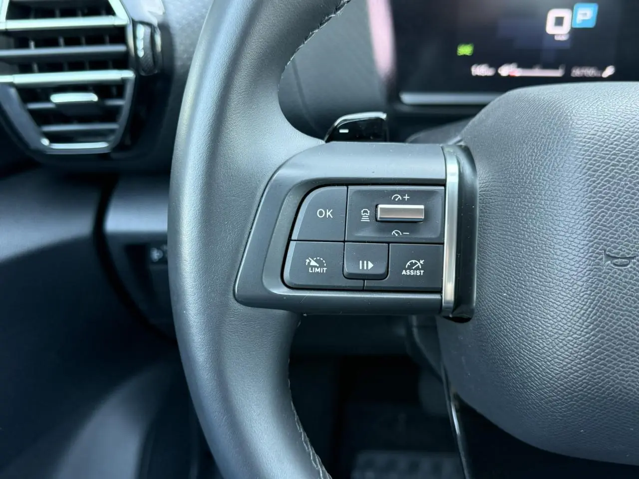 Gros plan sur les commandes du régulateur adaptatif au volant cuir noir du Citroën C4 X 2024.