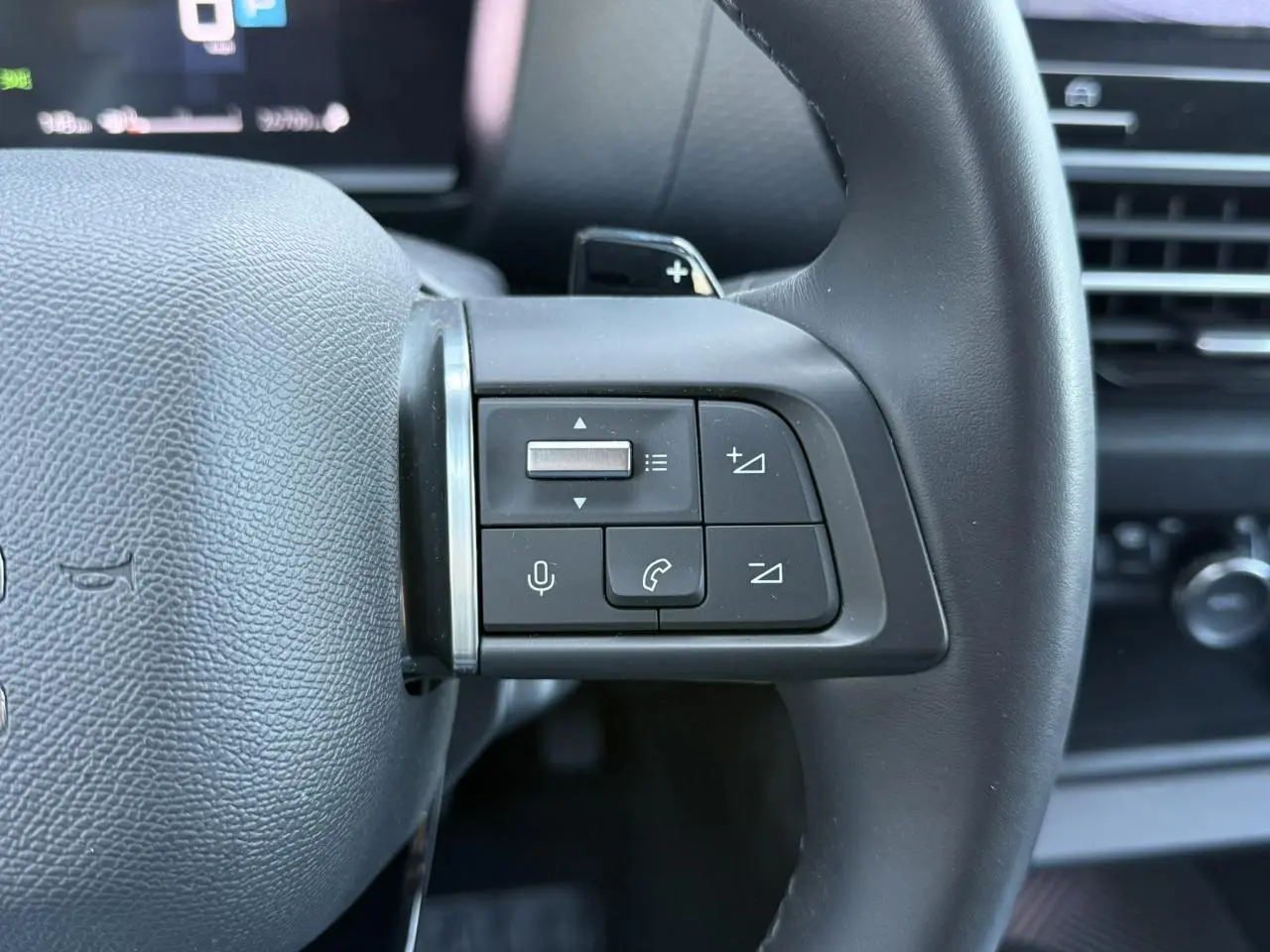 Gros plan sur les commandes audio et téléphone au volant cuir noir du Citroën C4 X 2024, intérieur moderne.