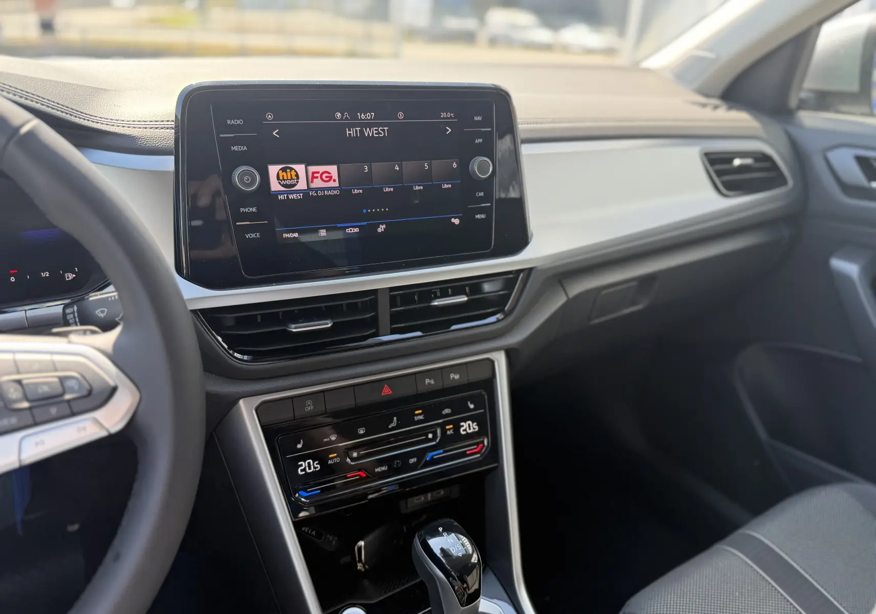 Intérieur du Volkswagen T-Roc 2025, vue du tableau de bord côté conducteur avec écran tactile et commandes climatisation.