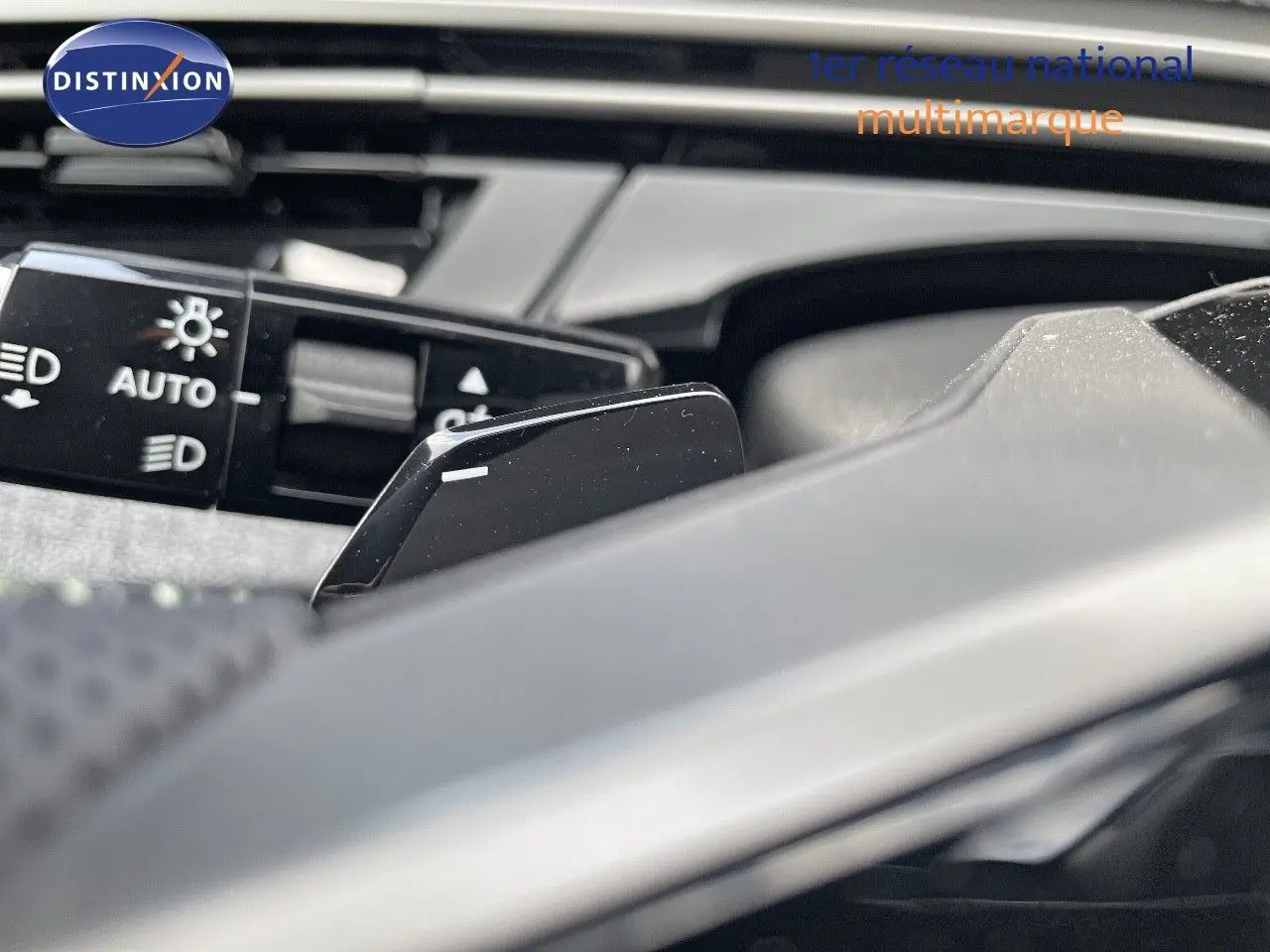 Gros plan sur la commande des feux automatiques et la palette de changement de vitesse dans un Peugeot 5008 noir perle métal 2025.