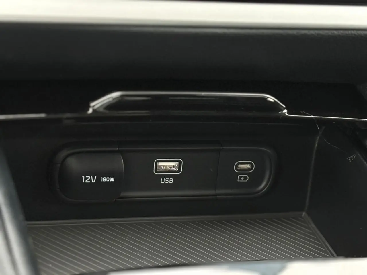 Prise USB, port USB-C et prise 12V intégrés dans la console centrale du Kia Sportage gris perle 2025.