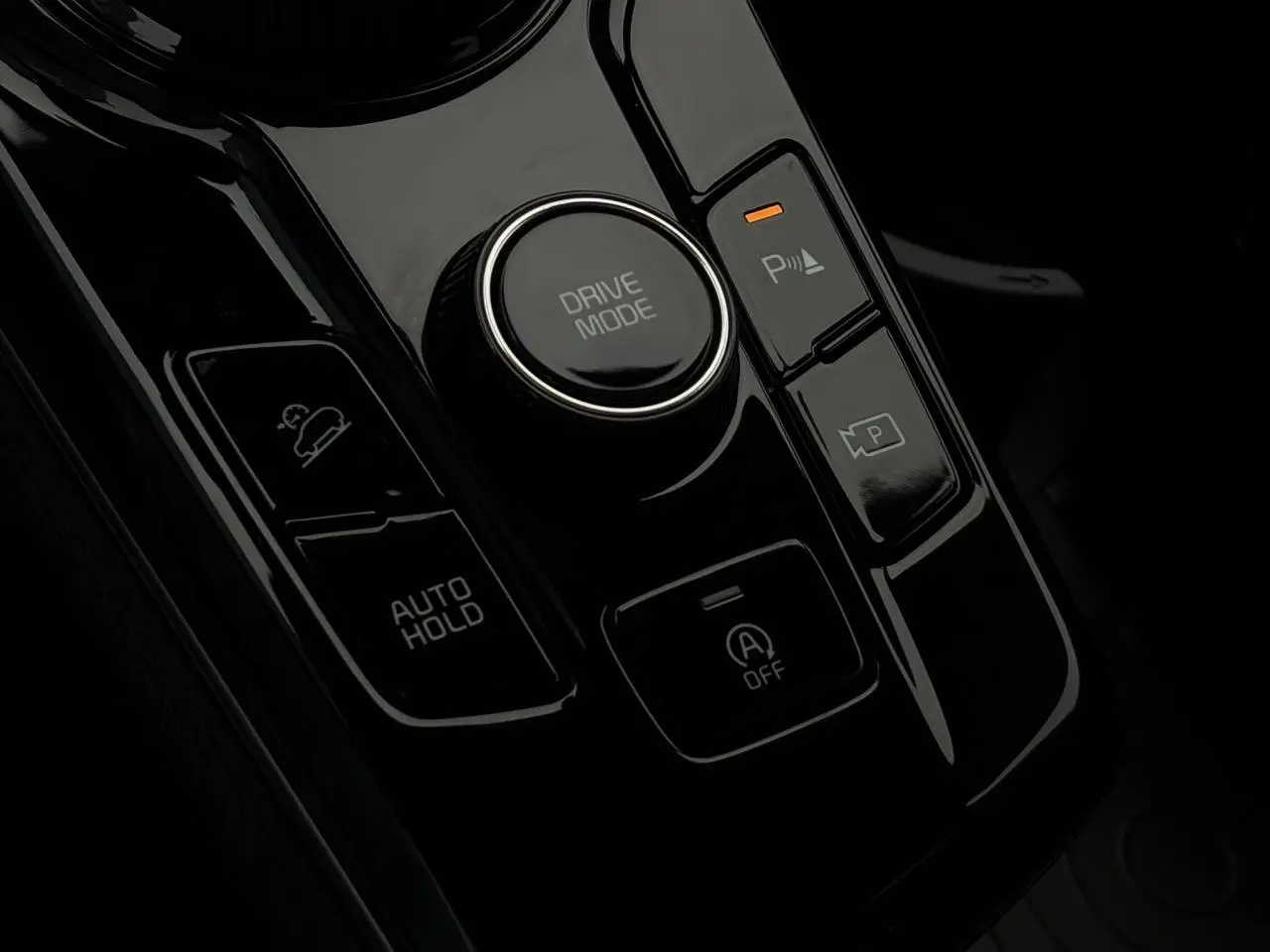 Gros plan sur la console centrale noire du Kia Sportage 2025 avec bouton Drive Mode et commandes Auto Hold.