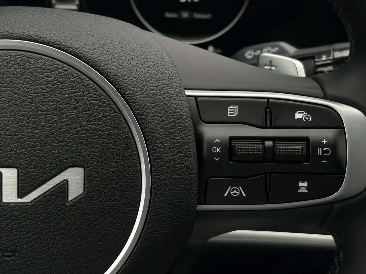 Gros plan sur les commandes à droite du volant cuir du Kia Sportage gris perle 2025, avec régulateur adaptatif.