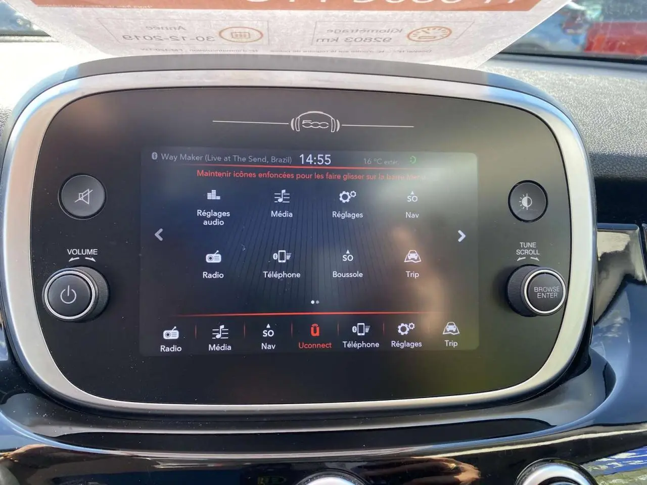 Écran tactile central de la Fiat 500X noir, affichant le menu multimédia avec commandes autour en vue frontale rapprochée.