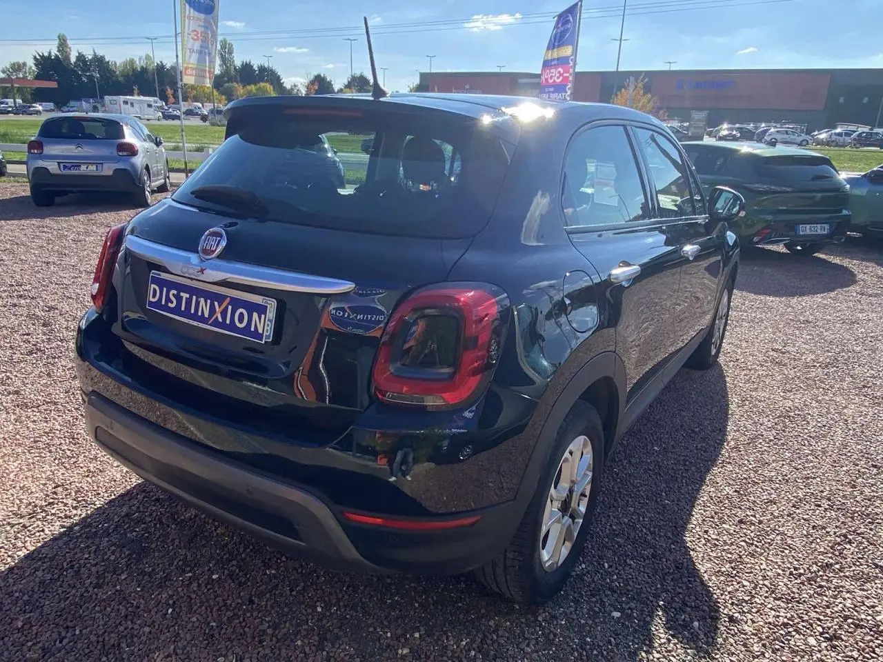 Vue 3/4 arrière droite d'une Fiat 500X noire métallisée avec jantes alliage 16 pouces sur parking extérieur.