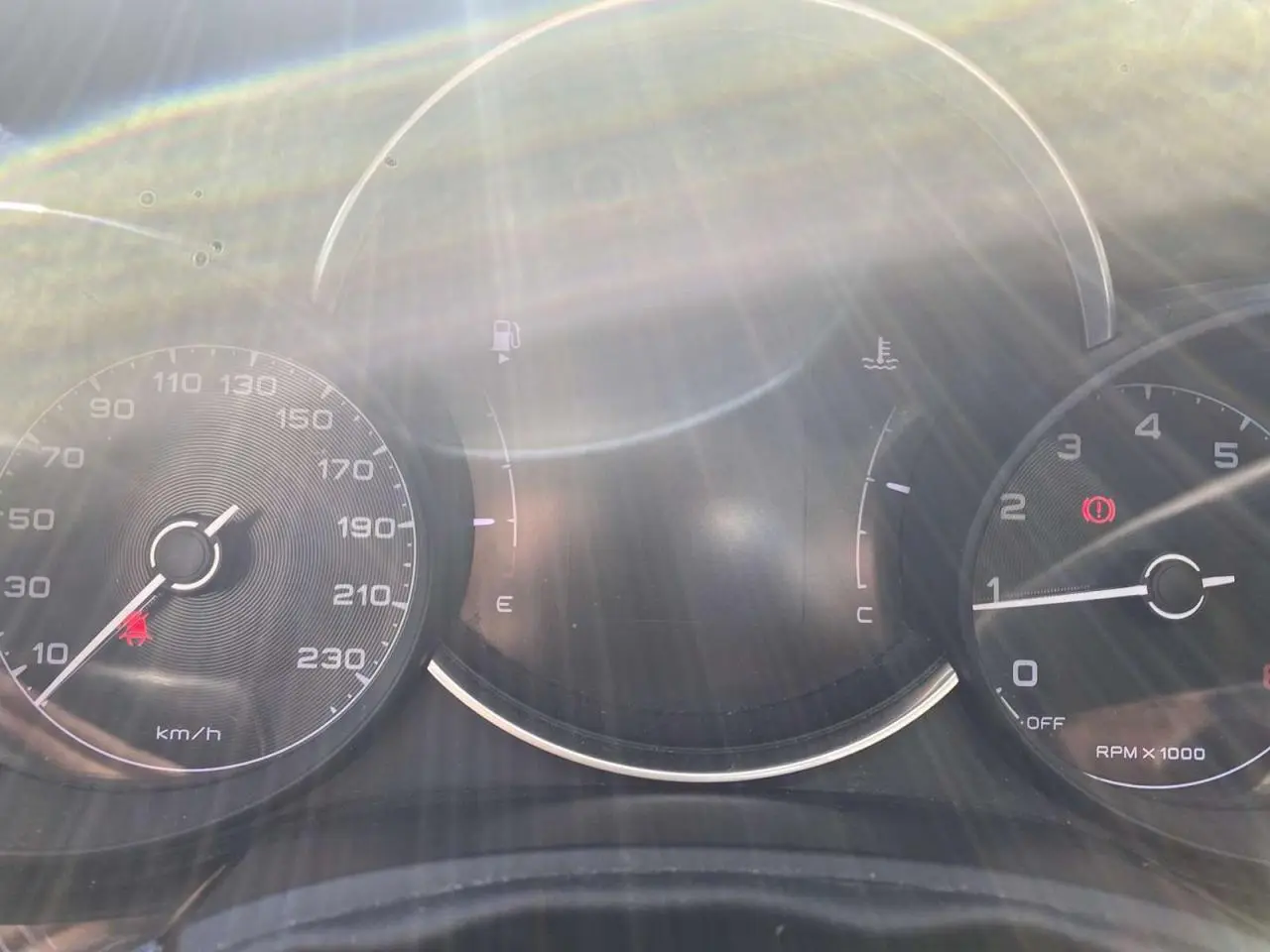 Tableau de bord de Fiat 500X noir 2019 avec compteur de vitesse, compte-tours et jauges sous un fort éclat lumineux.