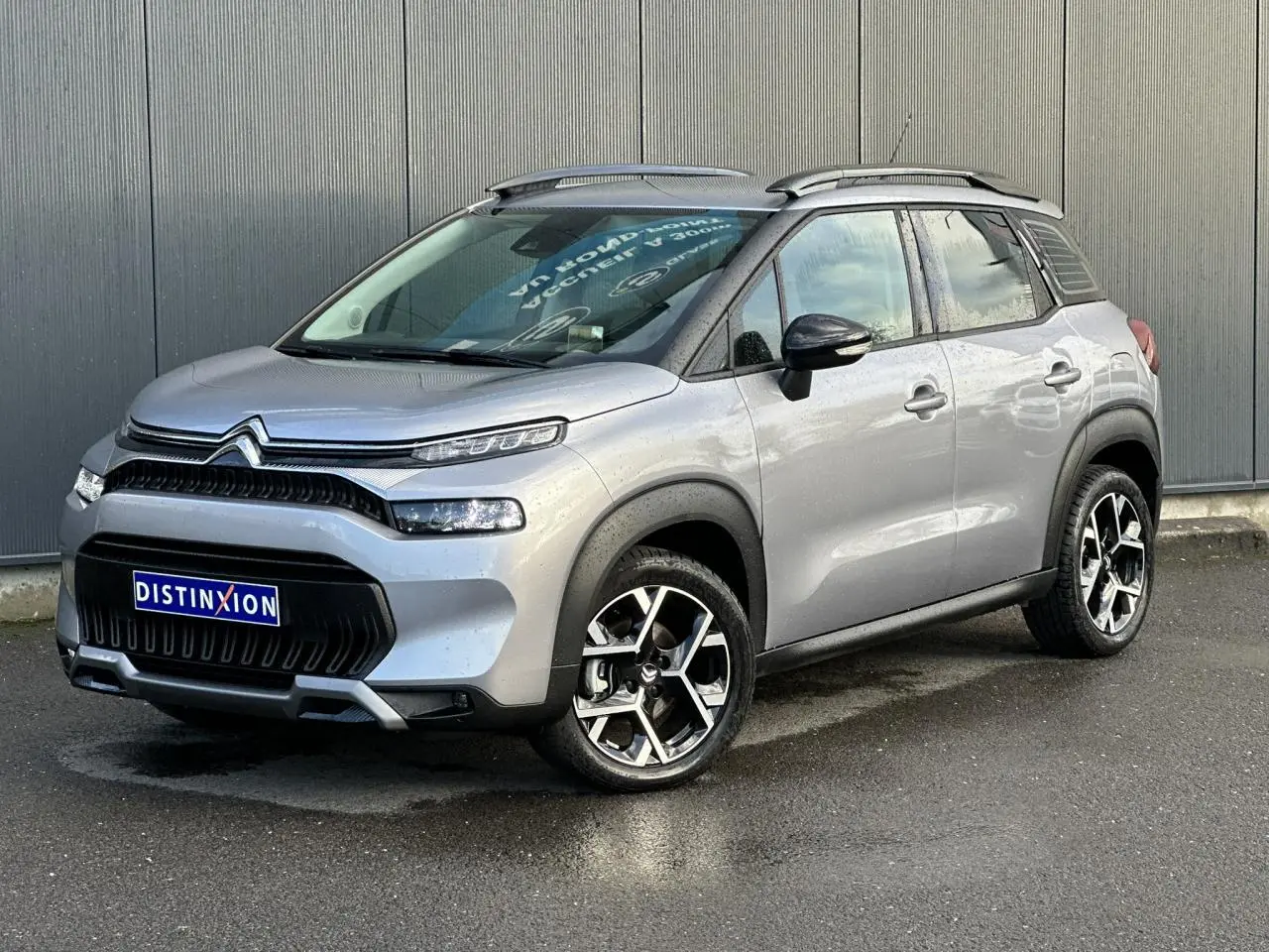 Citroën C3 Aircross gris Artense en 3/4 avant droit, avec jantes alliage 17'' et barres de toit noires.