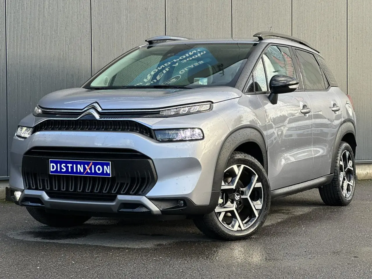 Citroën C3 Aircross gris Artense vue 3/4 avant droit, avec jantes alliage 17'' et barres de toit noires.