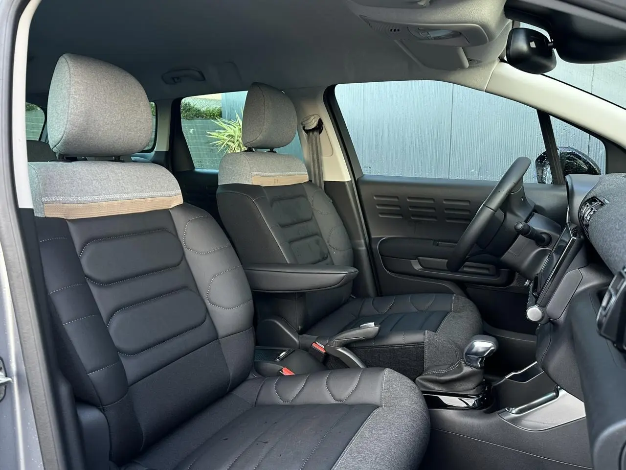 Vue intérieure côté droit de la Citroën C3 Aircross 2024, sièges avant en toile gris et noir avec accoudoir central.