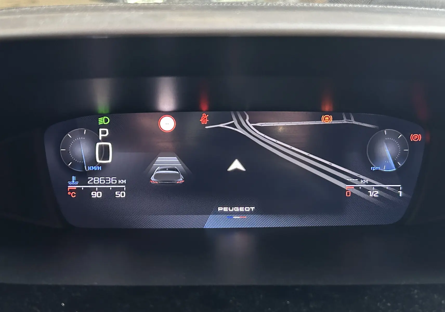 Tableau de bord numérique de Peugeot 308 rouge 2024, affichant la vitesse à 0 km/h et la navigation active.