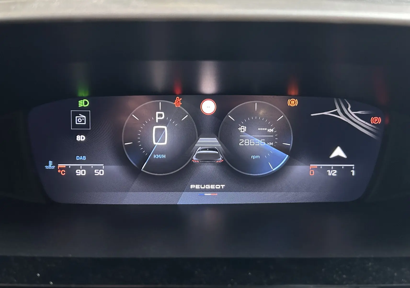 Tableau de bord numérique de Peugeot 308 rouge 2024, affichant vitesse, kilométrage et indicateurs divers.