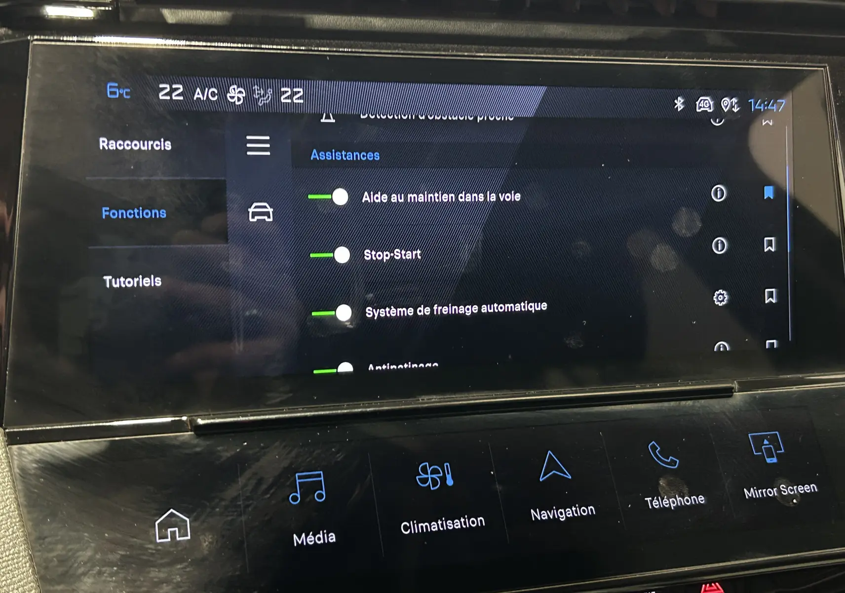 Écran tactile central de la Peugeot 308 rouge 2024 montrant les assistances à la conduite et les options multimédia.
