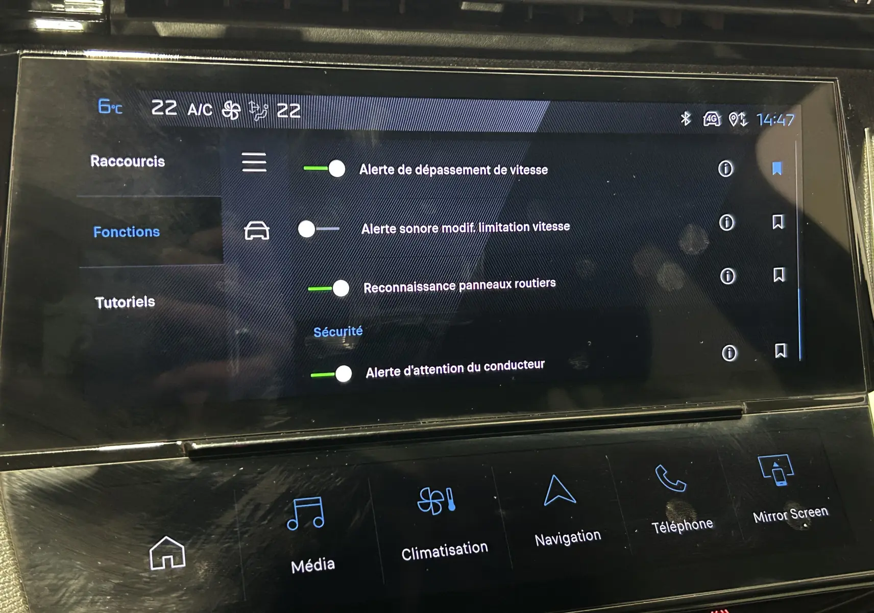 Écran tactile central de la Peugeot 308 rouge 2024 montrant les réglages d’alertes de sécurité et climatisation.