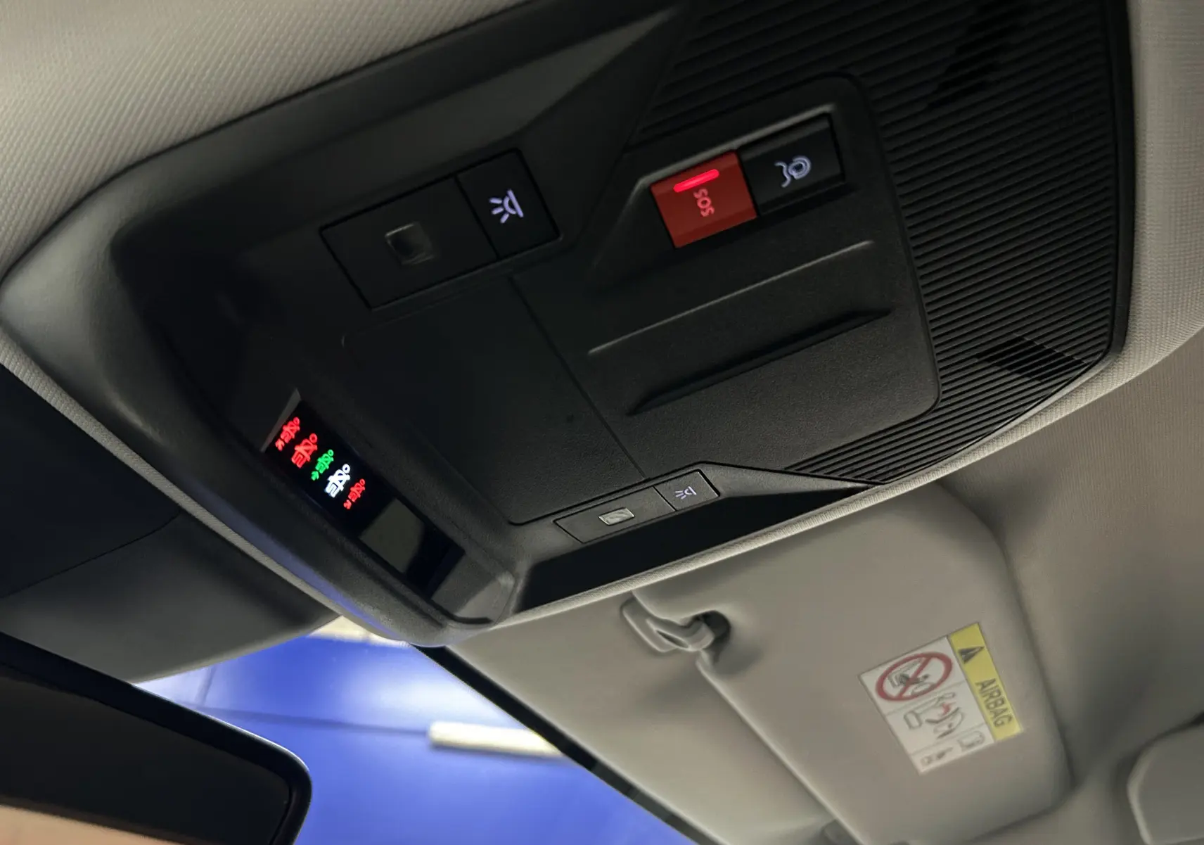 Vue intérieure en gros plan du plafonnier avec boutons SOS et éclairage, dans une Peugeot 308 rouge 2024.