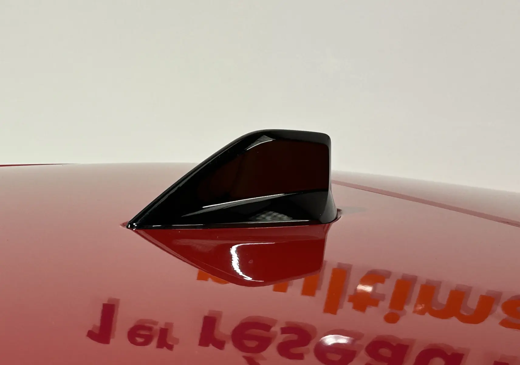 Antenne requin noire sur le toit rouge brillant d'une Peugeot 308 2024 vue en gros plan.