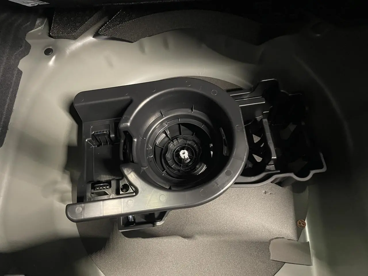 Détail du compartiment de rangement sous le coffre de la Peugeot 208 hybride 2025, montrant le support de roue de secours.