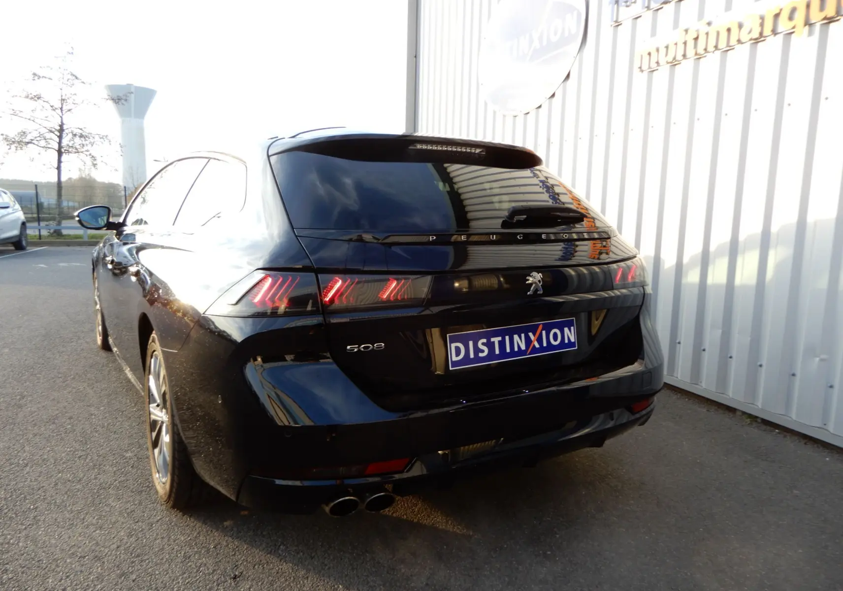 Vue 3/4 arrière droite d'une Peugeot 508 SW Allure noire Perla Nera avec feux arrière LED distinctifs et double sortie d'échappement.