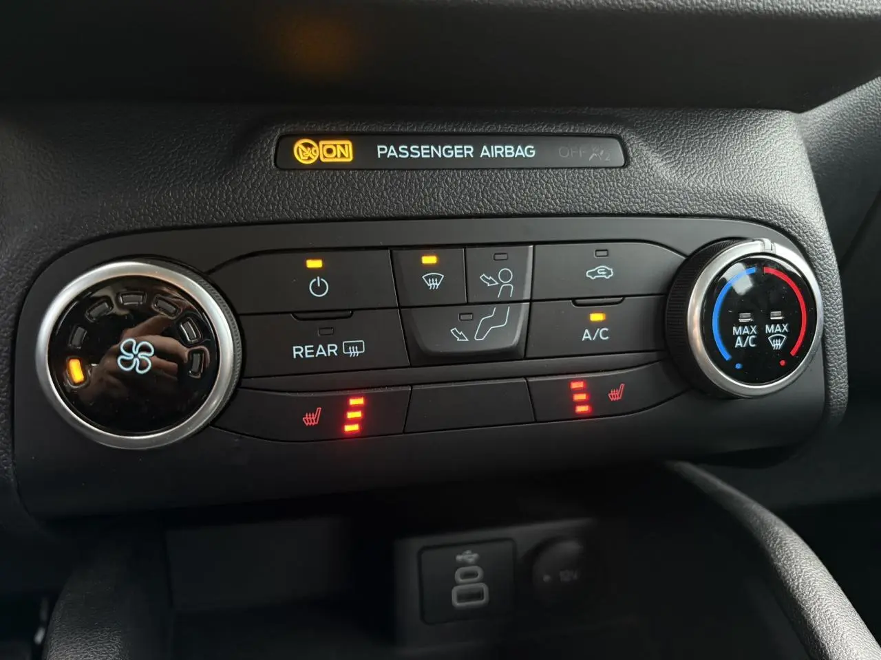 Gros plan sur la console centrale du Ford Kuga 2024 noir Obsidien, montrant les commandes de climatisation et sièges chauffants.