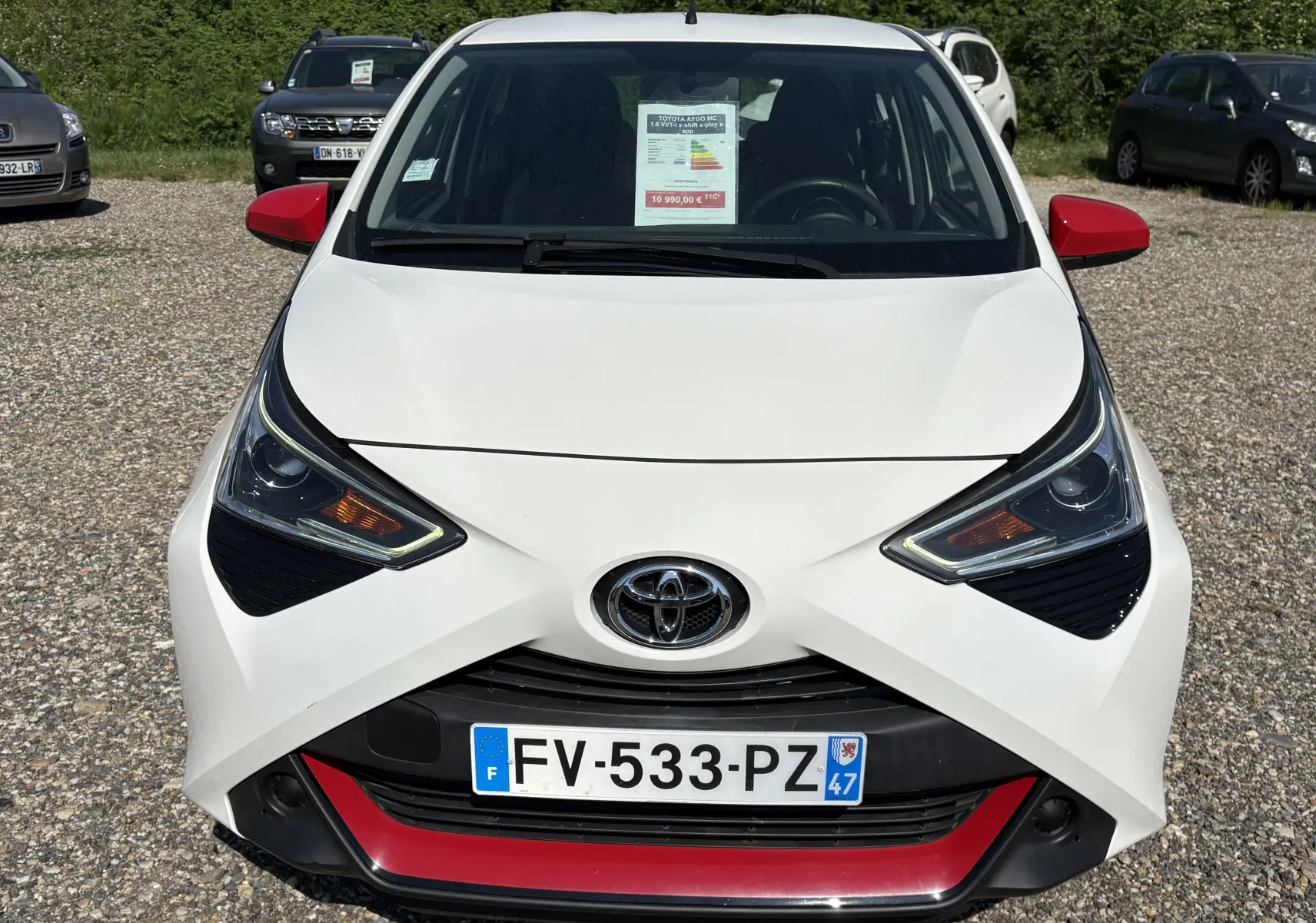 Vue avant d'une Toyota Aygo MC blanche 2020 avec rétroviseurs rouges et détails rouges sur le pare-chocs.