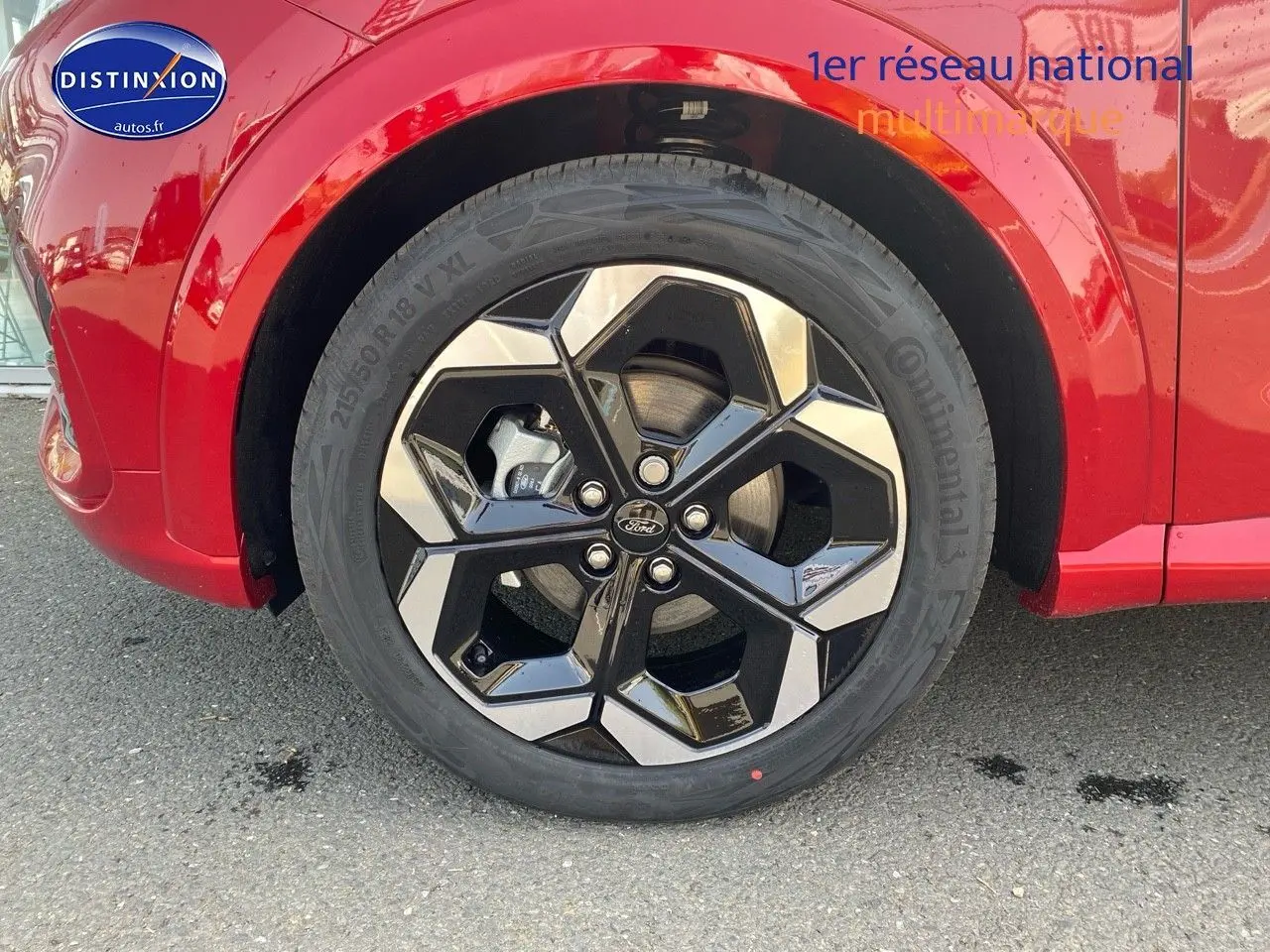 Gros plan sur la roue avant gauche avec jante alu noire et argent sur Ford Puma rouge métallisé.